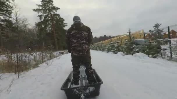 O inverno um trator rastejante monta crianças em um trenó através da floresta — Vídeo de Stock