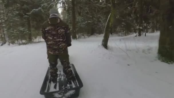 A tél egy kúszótraktor lovagol gyerekek egy szánkó az erdőben — Stock videók