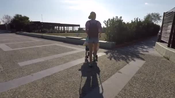 Летом по набережной ходит девочка с детской коляской — стоковое видео