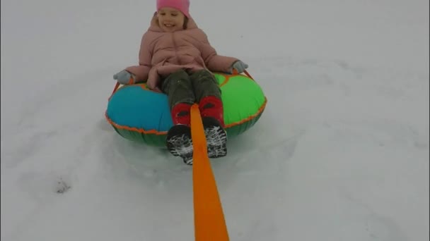 De winter een kind rijdt op een slang en valt van het — Stockvideo