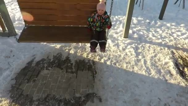 De winter een kind schommelt op een ketting schommel — Stockvideo