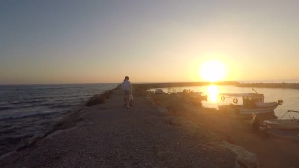 La fille avec la poussette marche le long de la jetée de pêche au coucher du soleil — Video
