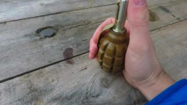 Adam elinde bir el bombası tutuyor ve emniyet kilidini açıyor.