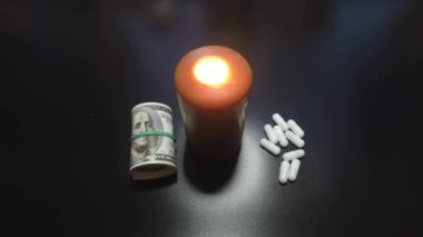 Siyah arka plan hapları, para ve sönmüş bir mum.