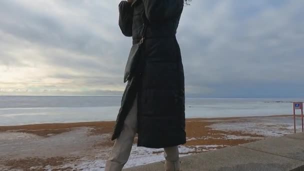 V zimě smutná dívka na břehu zamrzlého moře — Stock video