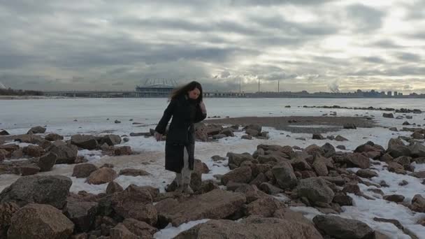 A menina fica sobre as rochas na costa do mar congelado — Vídeo de Stock