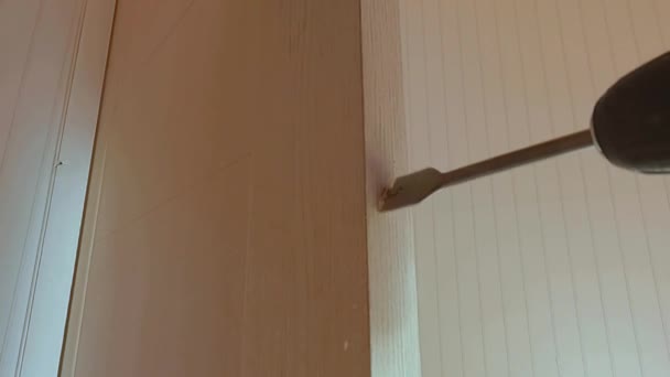 Byggaren gör ett hål i dörren för låset — Stockvideo