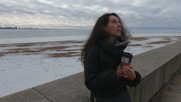 La chica en el terraplén en invierno con un vaso de café — Vídeos de Stock