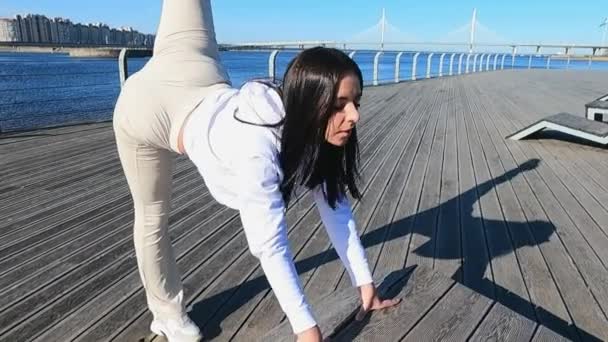 De op een zonnige ochtend een meisje op de dijk is bezig met fitness stretching — Stockvideo