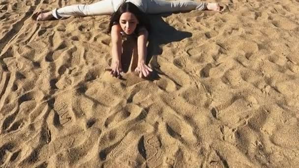 Na manhã em uma praia de areia uma menina faz exercícios de fitness alongamento ioga — Vídeo de Stock
