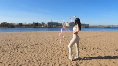 Kumsaldaki kız jimnastik kasetiyle meşgul.