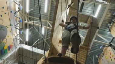 Çocuk bir halat macerası parkında bir engeli aşıyor.