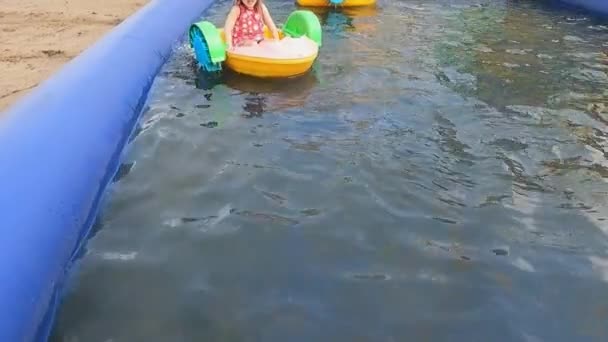 Slunečný letní den dítě dívka na vodě atrakce loď — Stock video