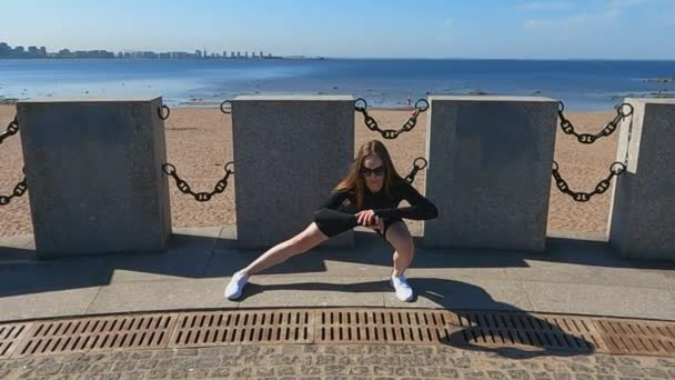 The girl doing fitness on the embankment exercise squats — Stock Video