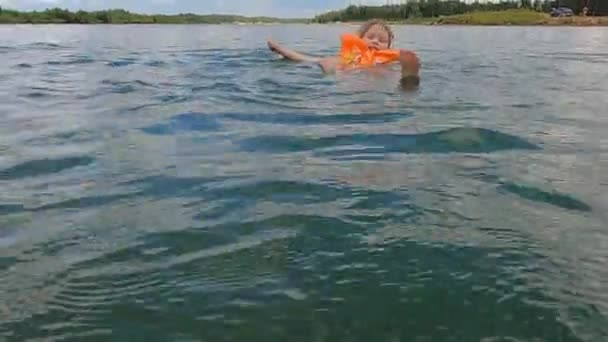 Het meisje zwemt in het water op een zonnige warme dag — Stockvideo