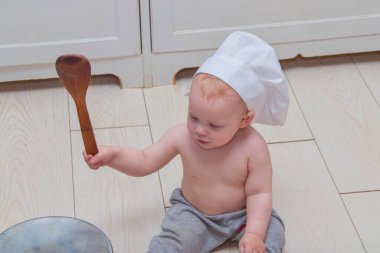 Kaşıklı ve tencereli bir aşçı kılığındaki bebek.