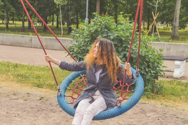 a girl swings on a swing in the park on a sunny day