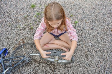 Bir kız çocuğu bisiklet tekerleğine zarar verdi ve işlemden geçmeden fotoğraf onarıyor.