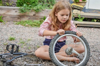 Bir kız çocuğu bisiklet tekerleğine zarar verdi ve işlemden geçmeden fotoğraf onarıyor.
