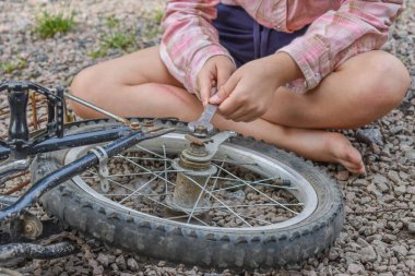 Bir kız çocuğu bisiklet tekerleğine zarar verdi ve işlemden geçmeden fotoğraf onarıyor.
