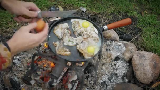 Man Friet Spek Eieren Met Specerijen Een Koekenpan Bij Rivier — Stockvideo