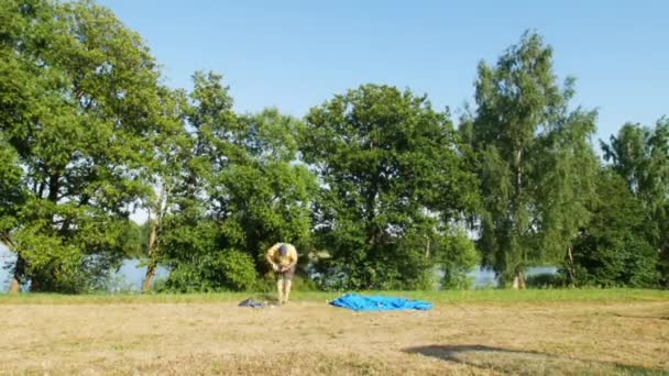 夏日阳光明媚的湖边 男性游客在草地上搭起了蓝色的帐篷 — 图库视频影像
