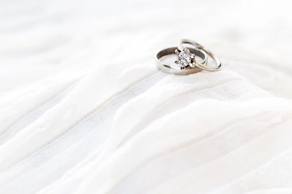 Golden wedding rings with diamond lie onwhite fabric. Symbol of love and marriage. — Stock Photo, Image