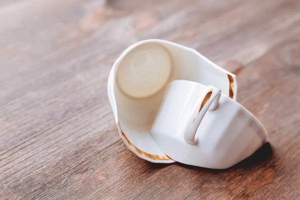 Gebroken witte cup op houten achtergrond. Beschadigde Mok met gouden decoratie. — Stockfoto