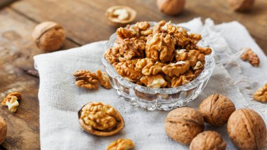 Rustik saf peçete üzerinde ceviz ile cam kase. Eski ahşap arka plan üzerinde sağlıklı snack.