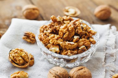 Rustik saf peçete üzerinde ceviz ile cam kase. Eski ahşap arka plan üzerinde sağlıklı snack.