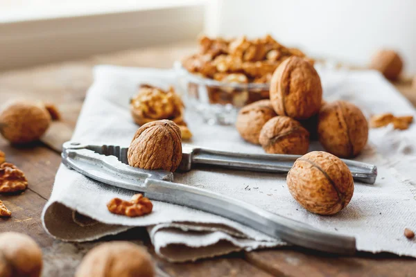 Glass bowl with walnuts on rustic homespun napkin. Healthy snack on old wooden background. — Stock Photo, Image