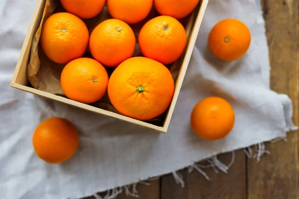 Caixa cheia de laranjas frescas. Colheita de frutas em mesa de madeira rústica . — Fotografia de Stock