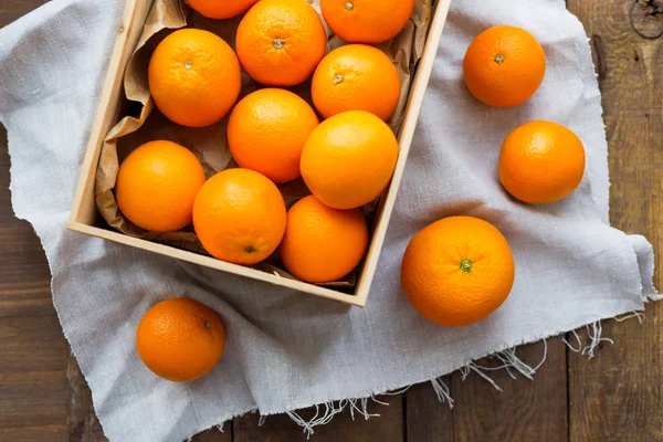 Caixa cheia de laranjas frescas. Colheita de frutas em mesa de madeira rústica . — Fotografia de Stock