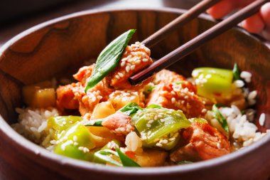 Asya Mutfağı - pirinç ile yağda kızarmış sebze, ananas ve somon ilave edin. Ahşap kase yemek çubukları ile. Yakın çekim.