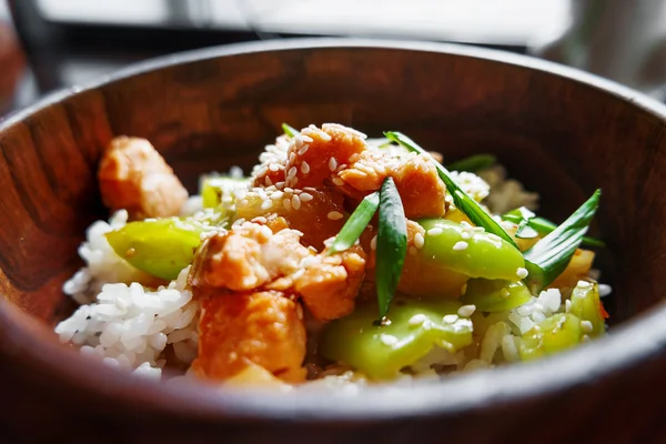 Aziatische keuken - rijst in saus met roer gebakken groenten, ananas en zalm in houten kom. Close-up. — Stockfoto