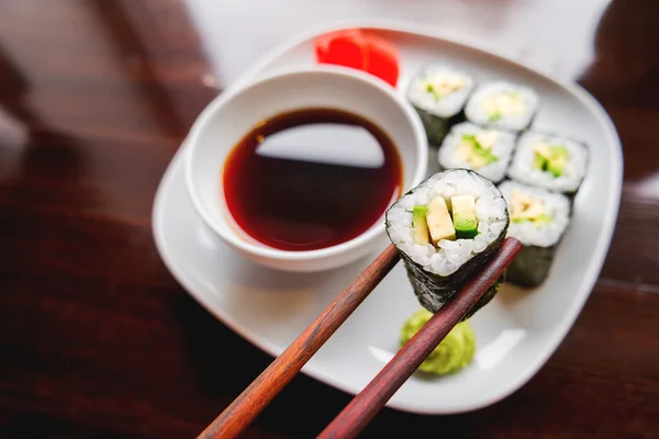 Rollos en algas nori con aguacate, jengibre en escabeche y salsa de soja. Cocina asiática, plato tradicional - sushi . — Foto de Stock