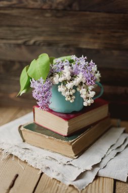 İki kitap ve saf peçete üzerinde leylak kokulu paslı kupa