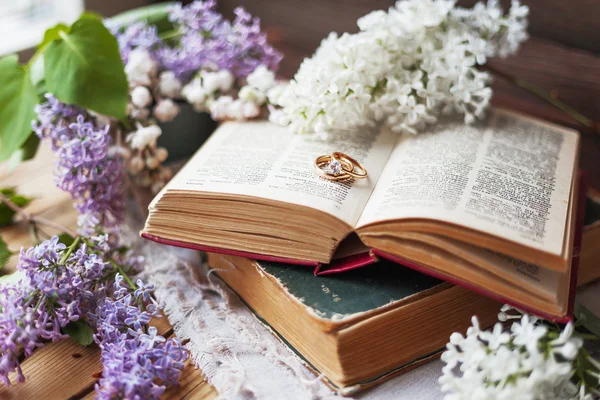 Paire d'alliances avec diamant. Fond rustique avec de vieux livres et des fleurs lilas. Fond rétro . — Photo