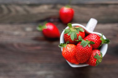 Bir kalp, aşk sembolü biçiminde kap taze sulu çilek. Rustik ahşap arka plan. Üstten Görünüm, metin için yer.