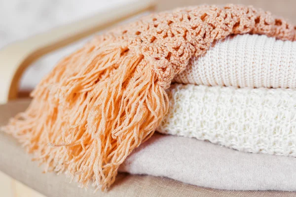 Pile of beige woolen clothes. Warm knitted sweaters and scarfs are folded in one heap. — Stock Photo, Image