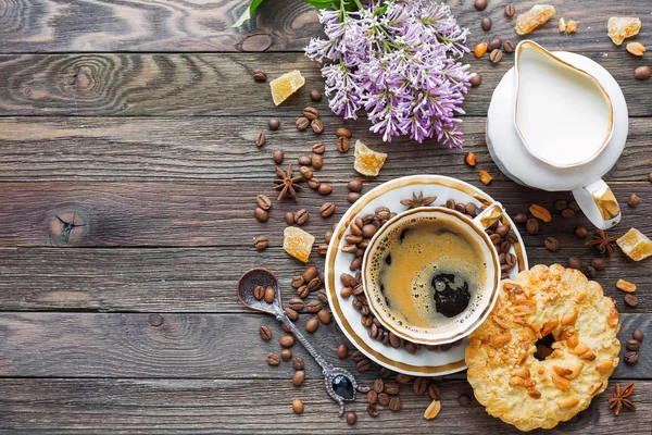 Rustieke houten achtergrond met kopje koffie, melk, pinda taart, suiker gember en lila bloemen. — Stockfoto