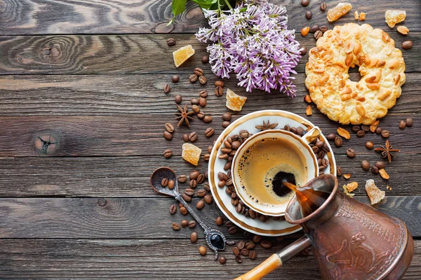 Rustieke houten achtergrond met cup en cezve van koffie, pinda taart en lila bloemen — Stockfoto