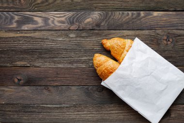 Beyaz kağıt torba içinde lezzetli ay çöreği. Şekerli tatlı ile rustik ahşap arka plan. Üstten Görünüm.