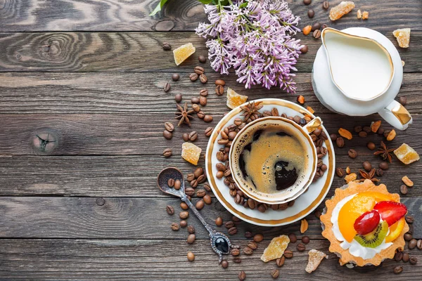 Rustic wooden background with cup of coffee, milk, fruit tart and lilac flowers. — Stock Photo, Image