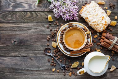 Rustik ahşap arka plan ile fincan kahve, süt, badem ezmesi topuz ve Lila çiçek.