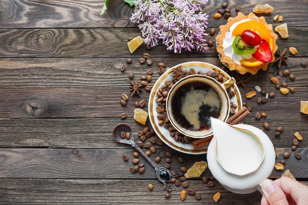 Latar belakang kayu berkarat dengan secangkir kopi, susu, tart buah dan bunga lilac . — Stok Foto