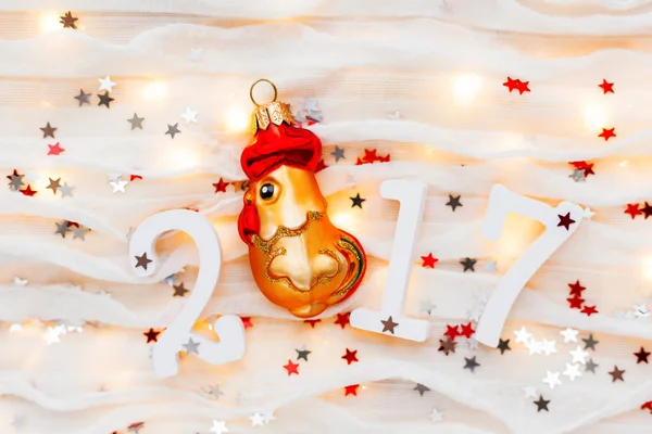 Christmas and New Year background with numbers 2017, decorations and light bulbs. Symbol of year - golden fiery rooster. — Stock Photo, Image