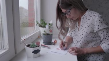 Kadın balkabağı ve hayalet çiziyor. Cadılar Bayramı için el yapımı süslemeler. Çiçek saksıları için DIY Boo çıkartmaları.