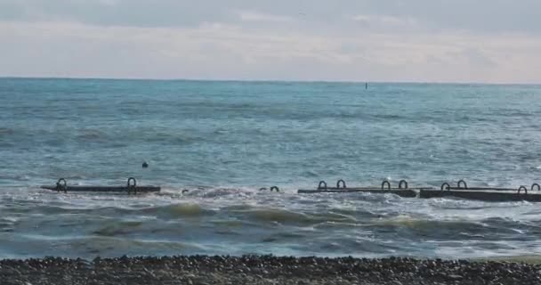 Mare surf su frangiflutti di cemento vicino alla spiaggia rocciosa. Tranquillo sfondo naturale nella giornata di sole. Mar Nero, Sochi, Russia. — Video Stock