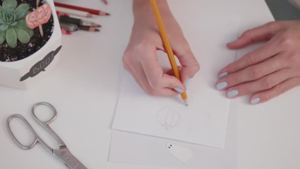 Frau mit blauem Nagellack zeichnet Geist in medizinischer Schutzmaske. Handgemachte Dekorationen für Halloween. DIY-Aufkleber für Blumentöpfe. — Stockvideo